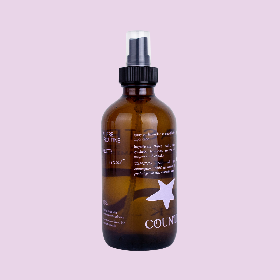 Back of Astral's amber glass bottle, showing one light purple star and light purple text that reads "where routine meets ritual. Spray on linen for an out of body experience. Ingredients: water, vodka, safe synthetic fragrance, essences of mugwort and celestite. Warning: Not safe for consumption. Avoid eye contact. If product gets in eyes, rinse with water. For full ritual, visit www.countermagick.com. Coven made- Salem, MA. @counter.magick"