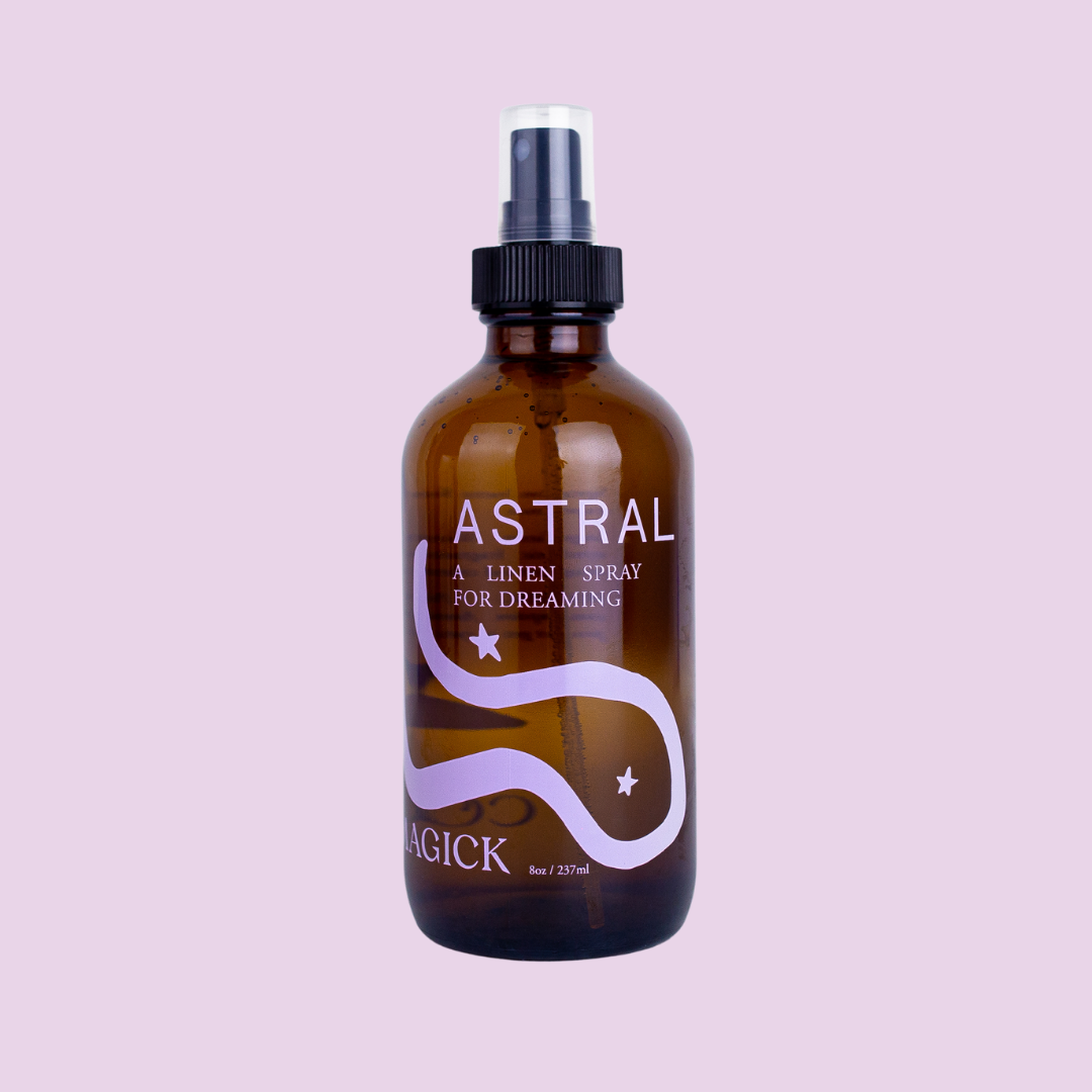 Astral: A Linen Spray for dreaming, in an amber glass bottle intentionally adorned with a minimalist swirling purple galaxy.
