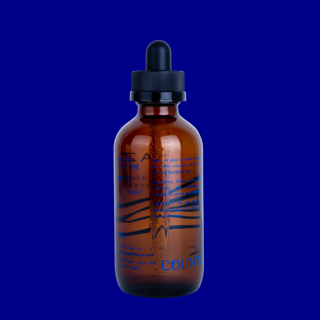 Back of Gaze's amber glass bottle, showing navy blue text that reads "Where routine meets ritual. Spray on glass to check yourself before you reflect yourself. Mix 1/3 bottle to 16 oz of distilled water. Ingredients: Vodka, water, plant-based surfactant, safe synthetic fragrance, essences of yarrow and obsidian. Warning: Not safe for consumption. Avoid eye contact. If product gets in eyes, flush with water. For full ritual, visit www.countermagick.com Coven made- Salem, MA. @counter.magick"