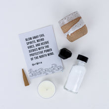 Load image into Gallery viewer, Contents of North Wind Spell Kit. Instruction card, handmade ceramic mini-cauldron, Black Tourmaline crystal, incense cone, tealight candle, and bottle of sea salt.
