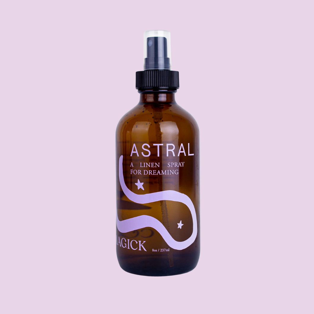 Astral: A Linen Spray for dreaming, in an amber glass bottle intentionally adorned with a minimalist swirling purple galaxy. 