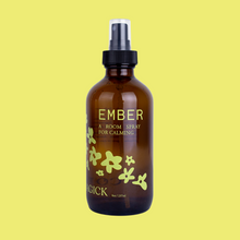 Load image into Gallery viewer, Ember: A Room Spray for calming, in an amber glass bottle intentionally adorned with a cascade of illustrated yellow daisy-type flowers. 8 oz/237 mL.
